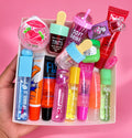 15-piece lip gloss and lip care bundle in a tray against a pink background